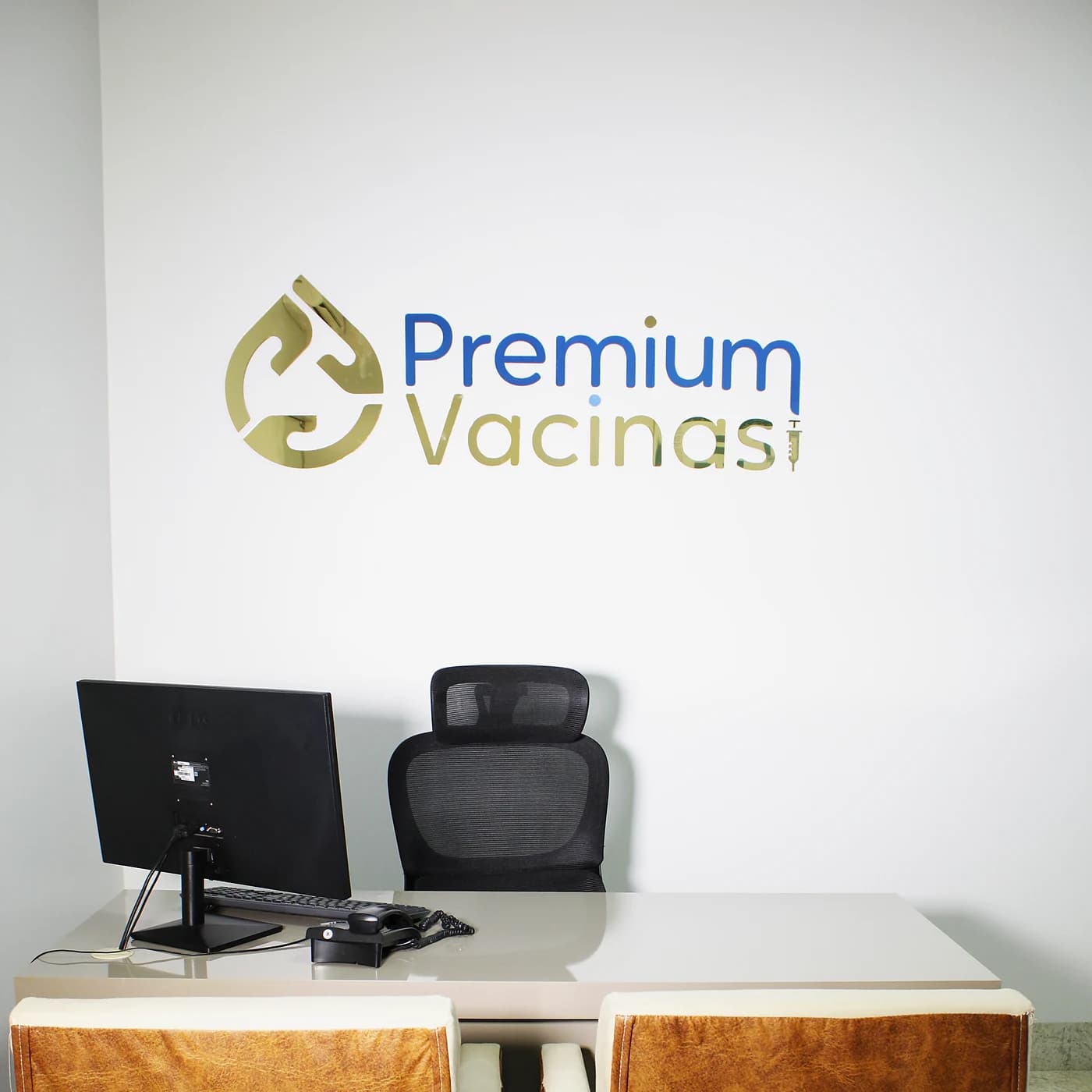 Sala da Premium Vacinas, com o logo na parede e a mesa de atendimento